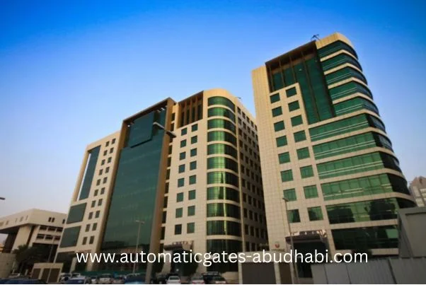 A view of two contemporary office buildings in Baniyas, Abu Dhabi, with sleek glass facades and a clear blue sky in the background.