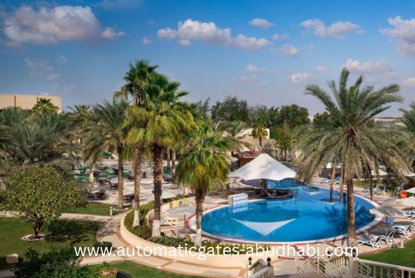A serene poolside view with palm trees surrounding a crystal-clear swimming pool in Al Mafraq, Abu Dhabi, under a bright blue sky.
