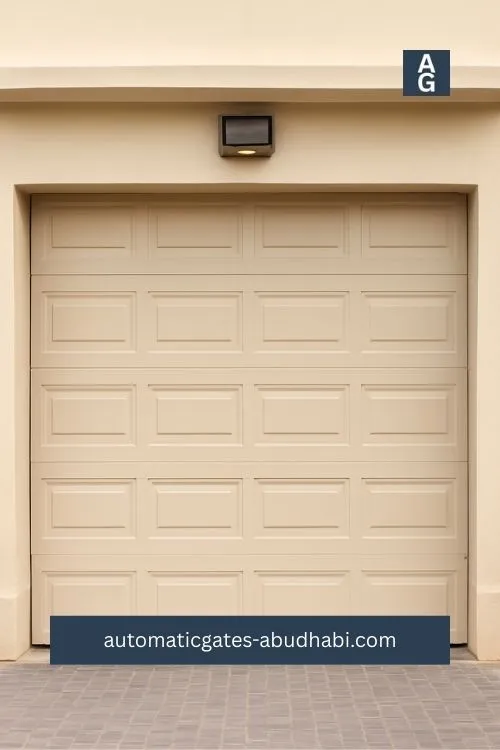 A beige sectional garage door with horizontal panels, featuring a black automatic opener mounted above in a clean and modern driveway in KEZAD, Abu Dhabi