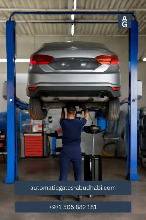 A mechanic working on a silver sedan lifted on a hydraulic lift in an auto repair garage, surrounded by tools and equipment.