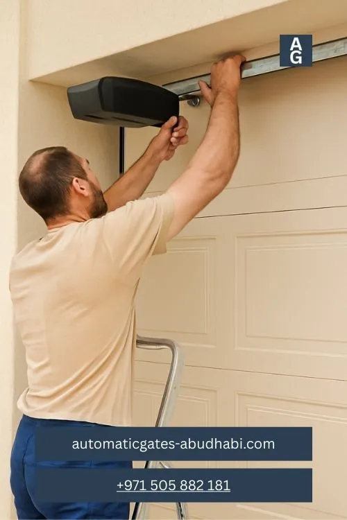 A technician installs an automatic garage door opener on a beige sectional garage door using a wrench, perched on an aluminum ladder in Khalifa Industrial.