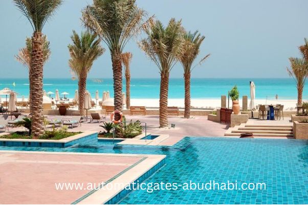 A stunning view of a resort pool with palm trees, leading to the pristine beach and turquoise waters of Saadiyat Island, Abu Dhabi.