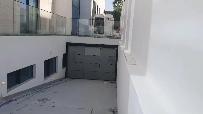 Dark panel sectional garage door at a villa basement ramp in Abu Dhabi